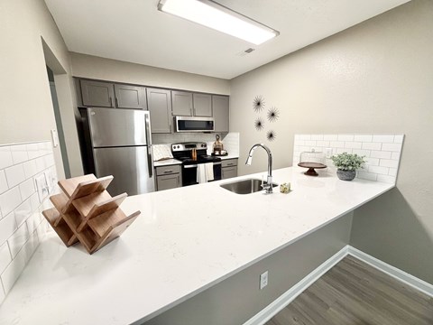 A kitchen with a white countertop and a stainless steel refrigerator.