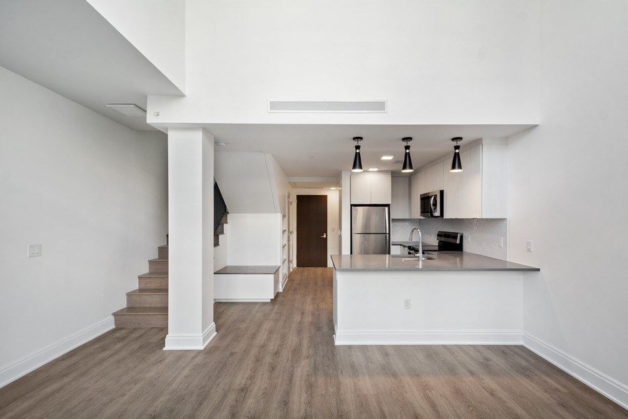 an empty living room with a kitchen and stairs
