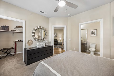 A bedroom with a large bed and a dresser with a mirror above it.