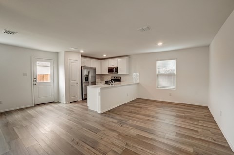 Generously sized living room seamlessly integrated with an open kitchen equipped with a pantry, windows, and a convenient connection to the backdoor