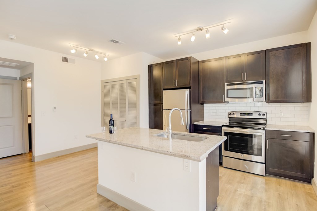 a kitchen with a large center island with a sink and a stove top oven