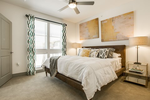 A bedroom with a large bed and a ceiling fan.