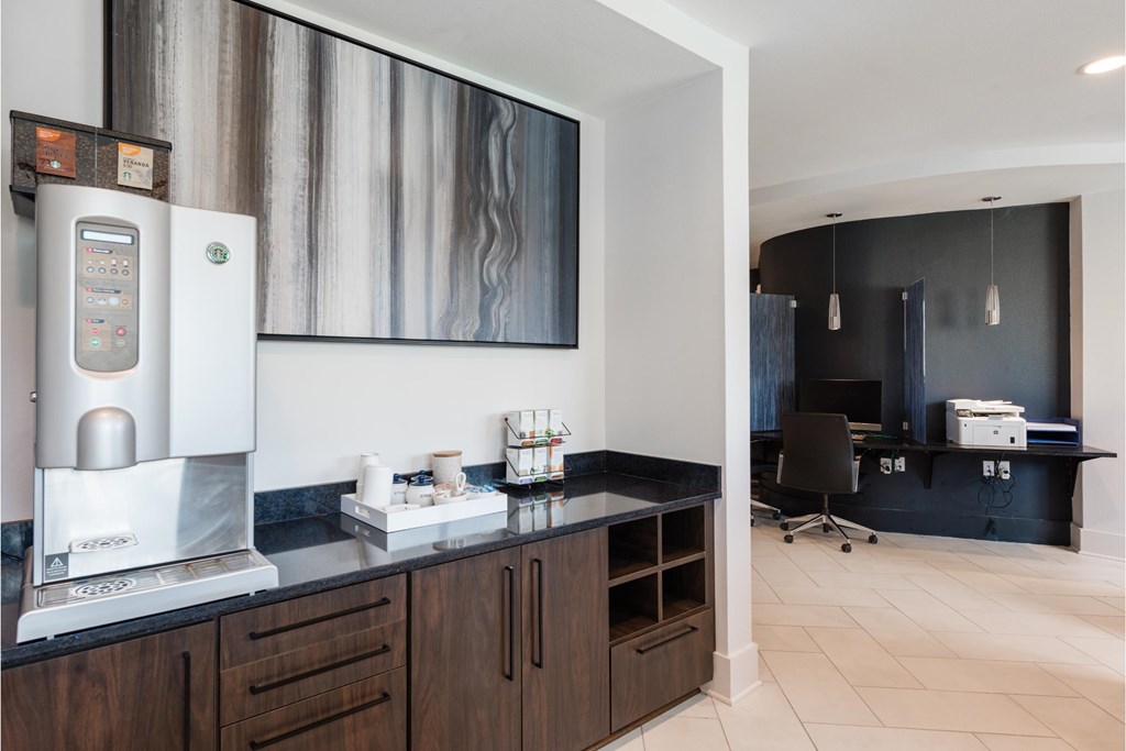 a kitchen with a coffee machine and a desk in a hotel room