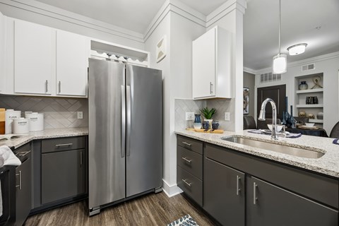 A modern kitchen with a stainless steel refrigerator and dark grey cabinets.