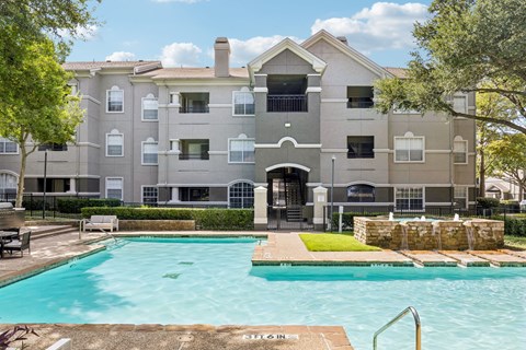A large apartment complex with a pool in front.