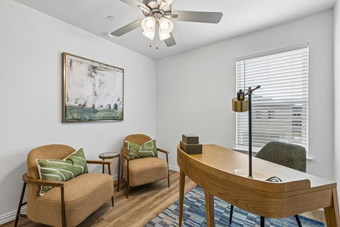 A living room with a painting on the wall and a ceiling fan.