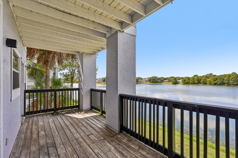 A balcony with a view of a lake and trees.