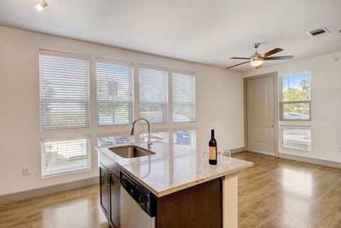 a kitchen with a sink and a counter top in front of windows