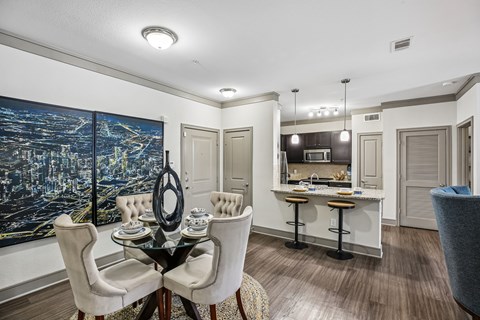 A dining room with a table set for two and a cityscape on the wall.