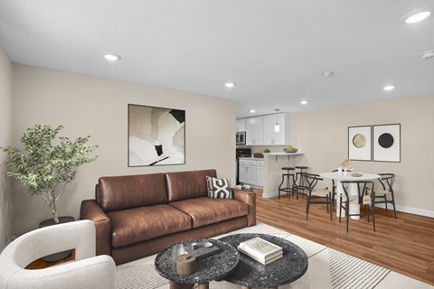A living room with a brown couch, a coffee table, and a dining area in the background.