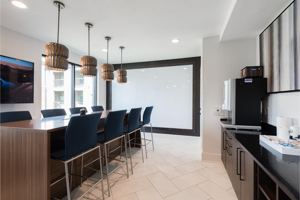 a kitchen and dining room with blue chairs and a long bar and a large window
