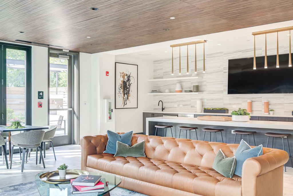 A living room with a brown leather couch and a glass coffee table.
