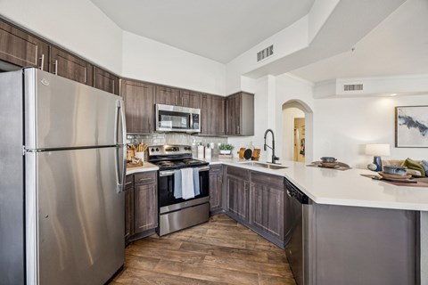 A modern kitchen with a stainless steel refrigerator and wooden cabinets.