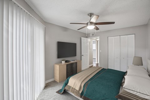 A bedroom with a bed, a television, and a ceiling fan.