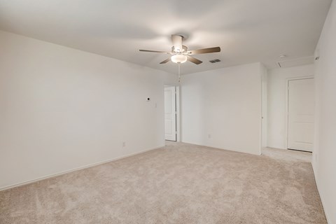 Ample bedroom space with carpet flooring and a central ceiling fan for added comfort and circulation.