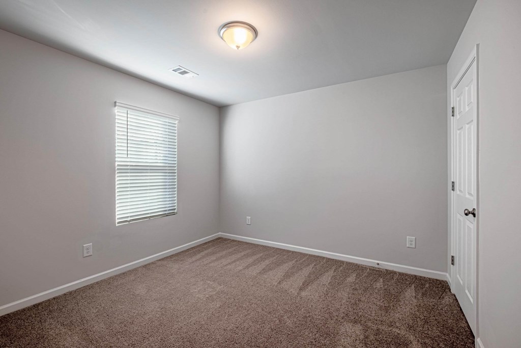 an empty room with carpet and a window and a door