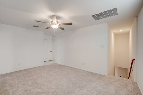 Well- lit, carpet loft area with stairs to the lower floor