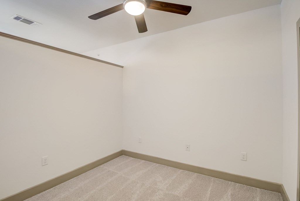 a bedroom with white walls and a ceiling fan