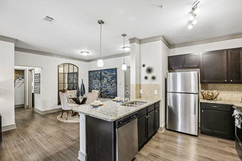 A kitchen with a stainless steel refrigerator and black cabinets.