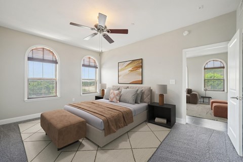 A bedroom with a large bed and a ceiling fan.
