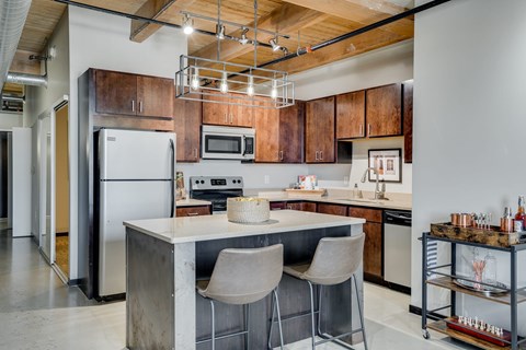 a kitchen with a center island with two chairs and a refrigerator