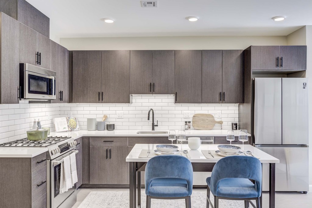 A modern kitchen with a white table and blue chairs.