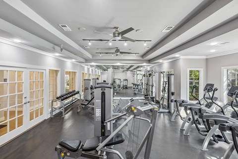 A spacious gym with a variety of equipment and a ceiling fan.