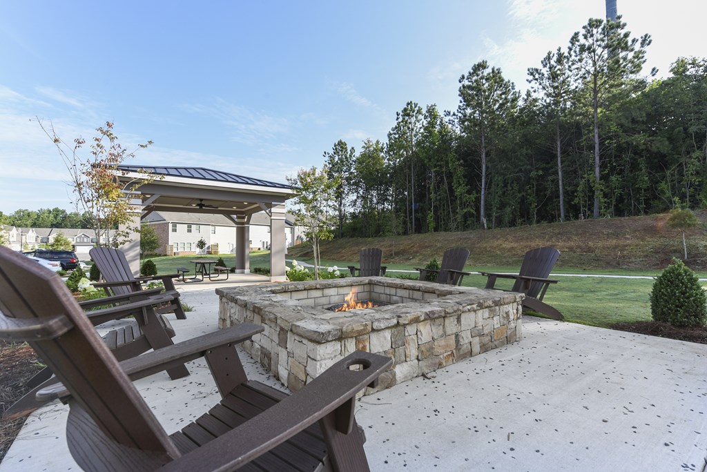 a patio with a fire pit and chairs and a pavilion