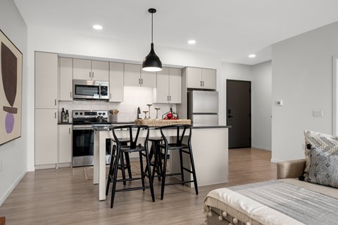 A modern kitchen with a dining area and a bed in the corner.