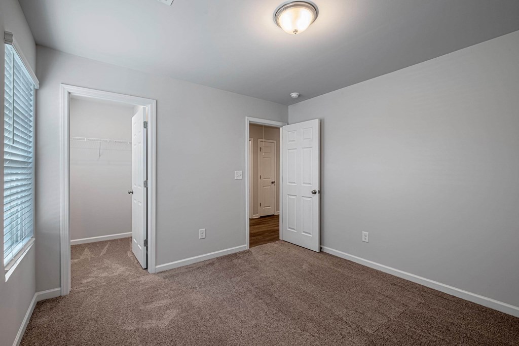 a room with a carpeted floor and a door to a closet
