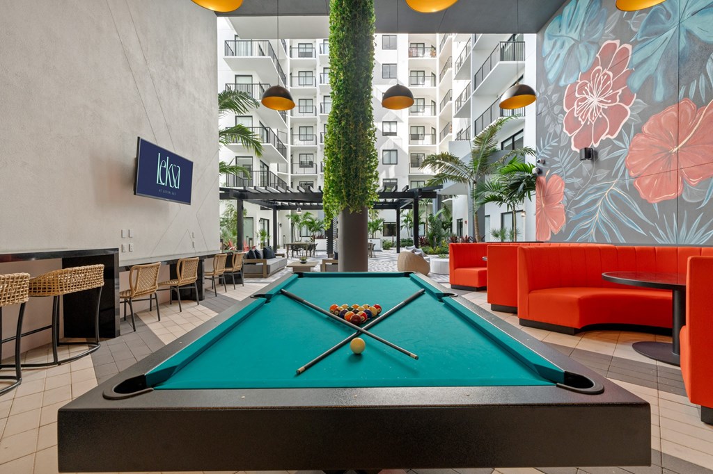 A pool table in the middle of a room with a sign that says "Idk" on the wall.