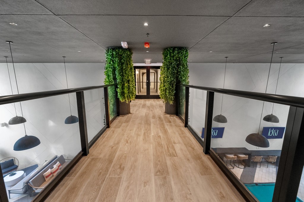 A long hallway with plants on the sides and hanging lights.