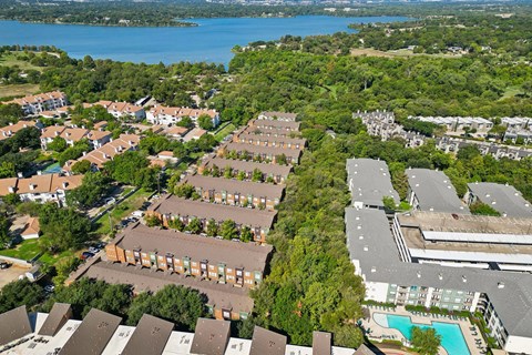A bird's eye view of a residential area with a swimming pool and a lake in the background.