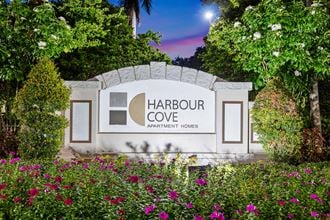 a sign for the harbour cove development house with flowers