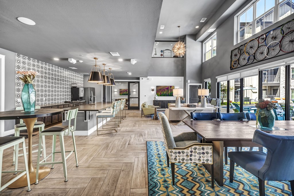 a communal area with tables and chairs in a building with large windows