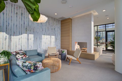 A living room with a blue couch and a woven ottoman.