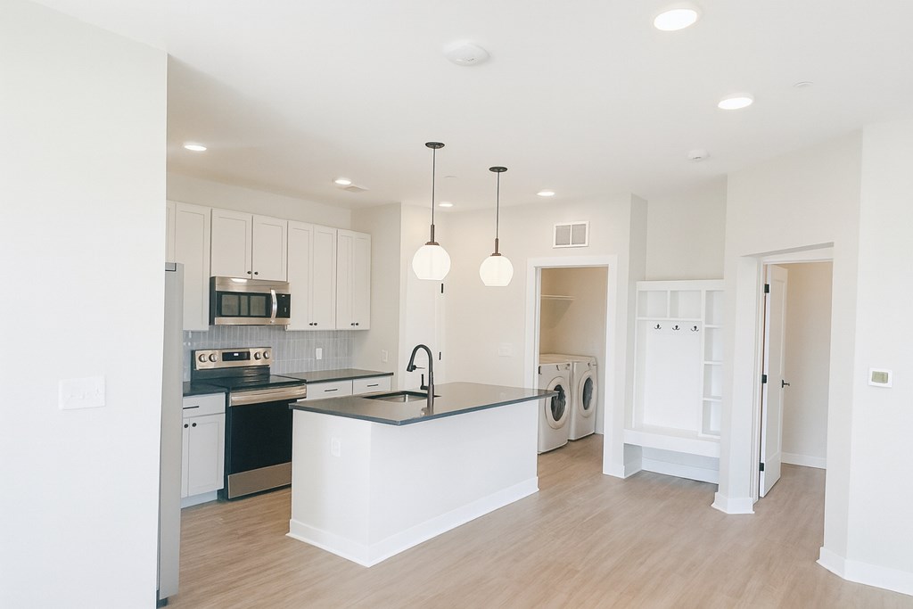 A modern kitchen with a large island and pendant lights.