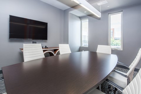 a conference room with a large table and chairs and a television