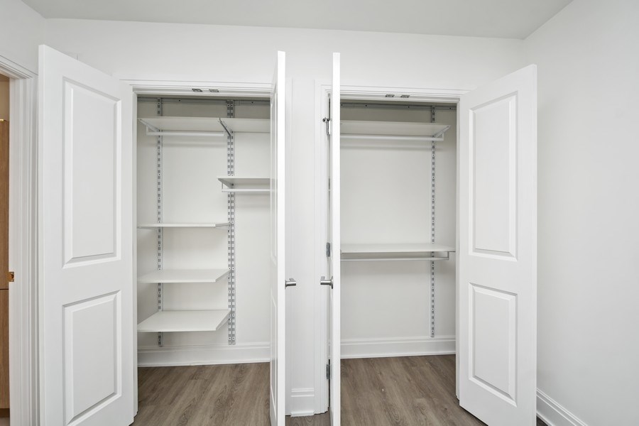 an empty closet with white doors and white walls and wood floors
