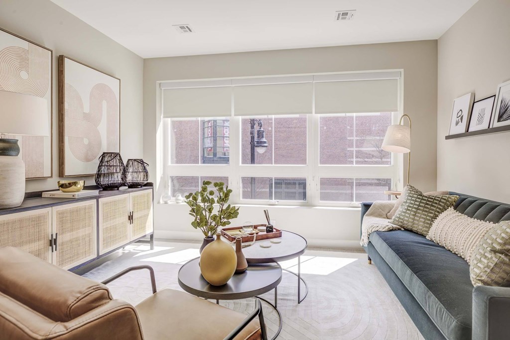A living room with a couch, chairs, and a table with a vase and plant on it.