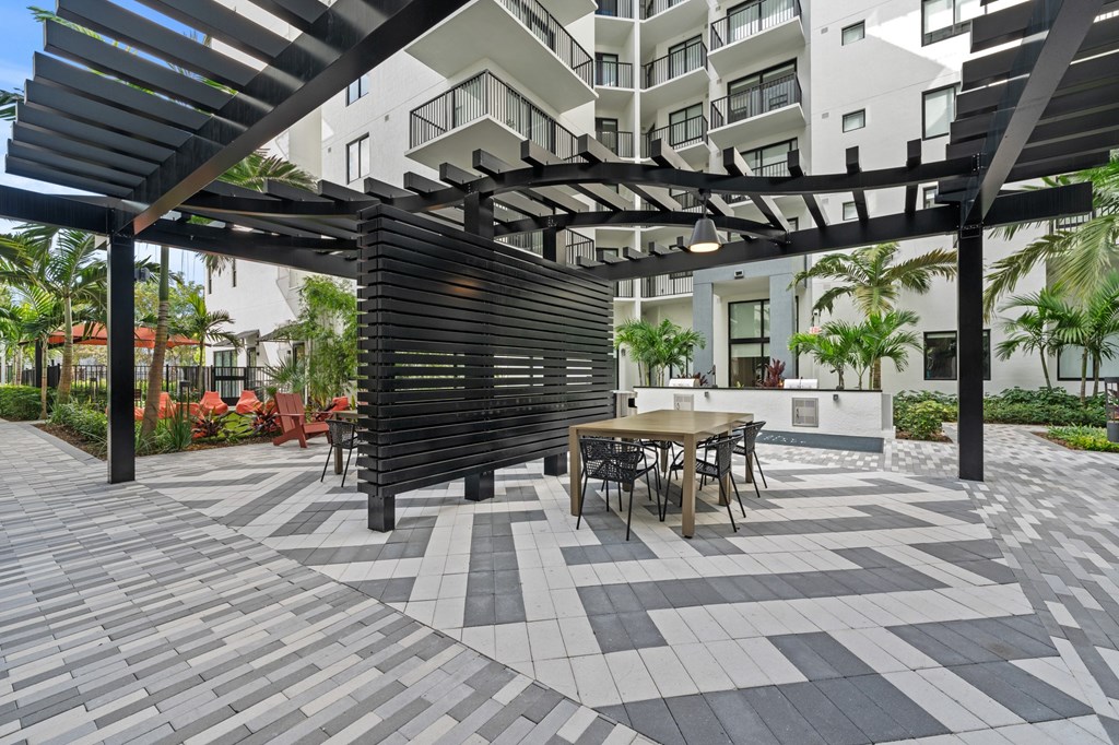 A patio with a table and chairs under a black pergola.