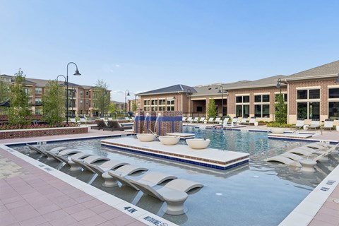 A pool with a blue tiled edge and white lounge chairs.