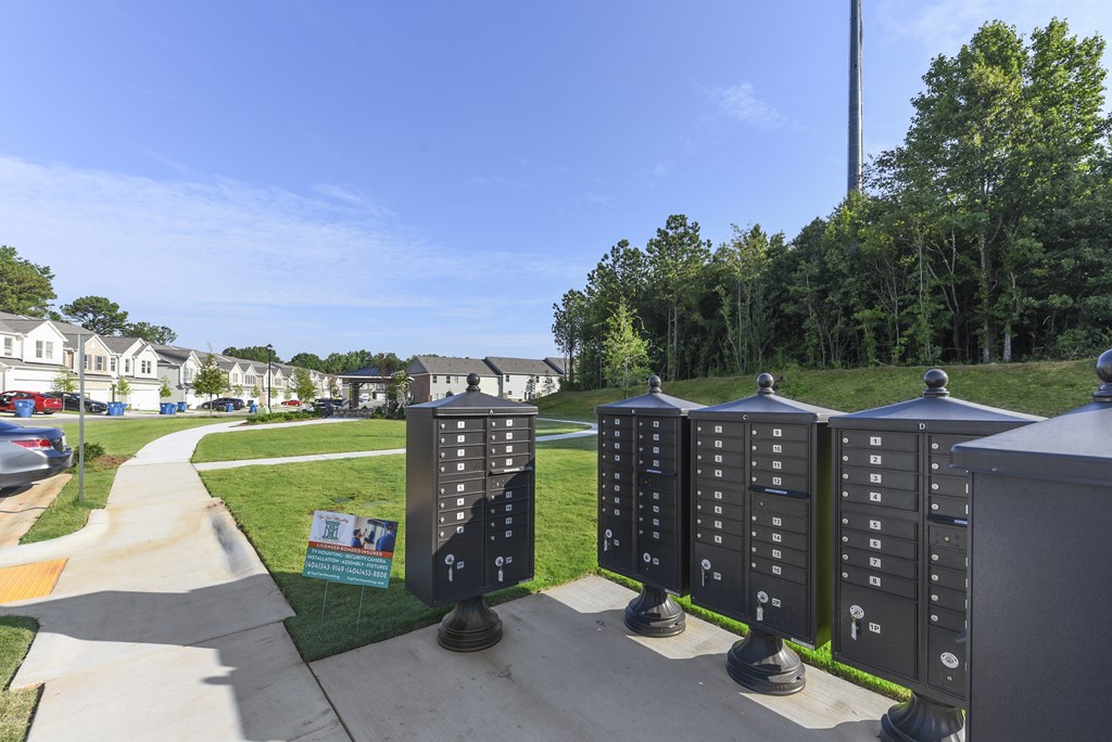 a row of mailboxes sit on a sidewalk in front of a street with houses
