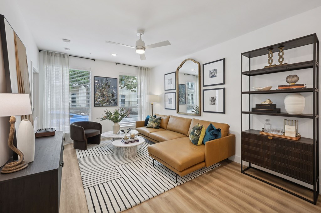 A living room with a brown sofa and a black and white striped rug.