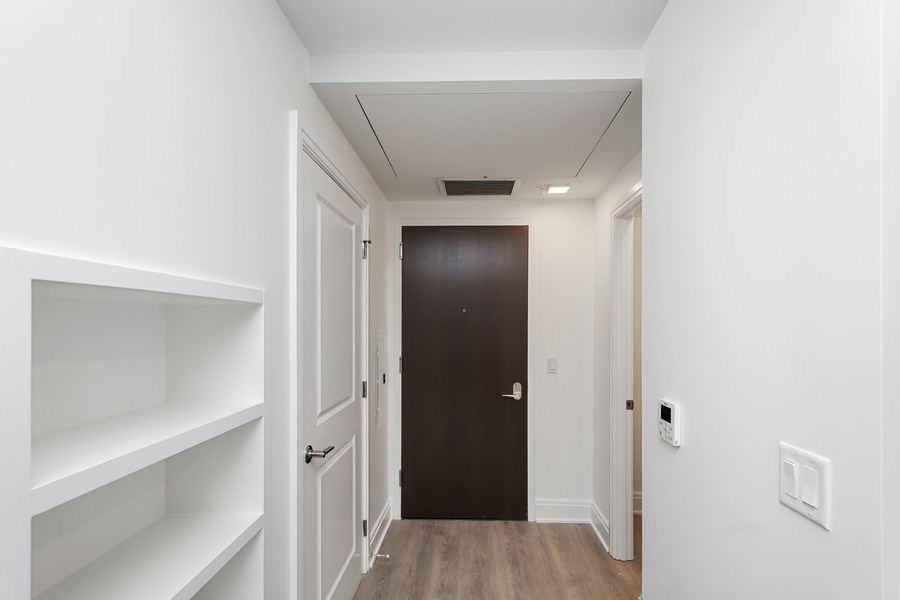 a hallway with white walls and a black door     and white shelves