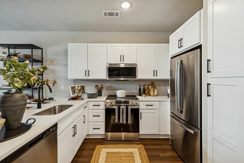A modern kitchen with white cabinets and stainless steel appliances.