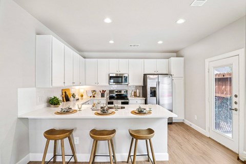 A kitchen with white cabinets and a white island with bar stools.