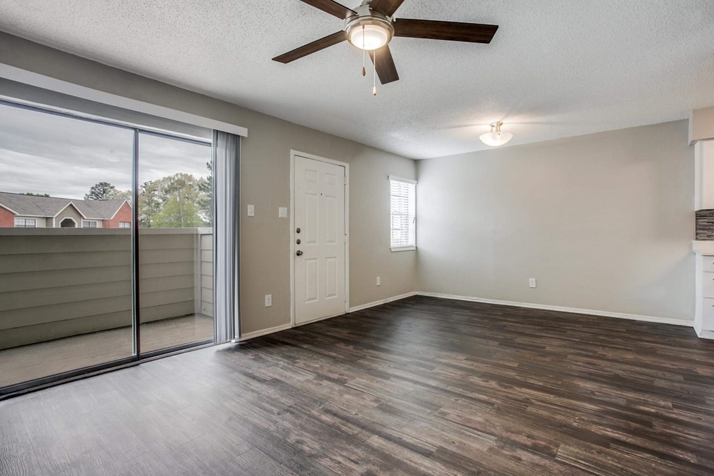 an empty living room with a sliding glass door and a ceiling fan