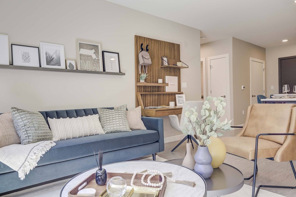 A living room with a grey couch, a coffee table, and a wooden shelf.