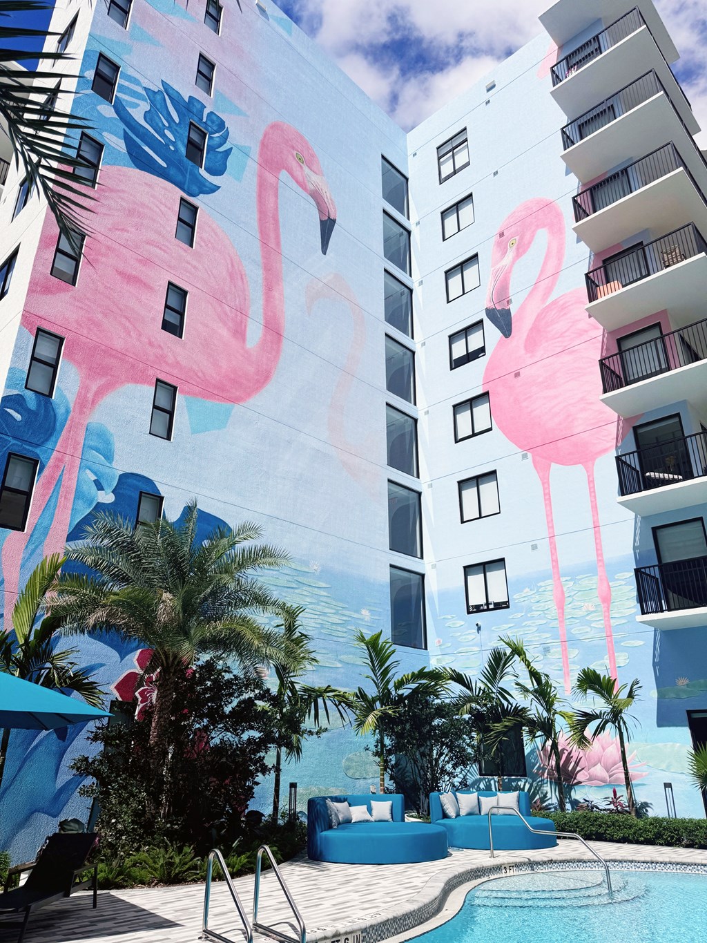 A mural of a pink flamingo is painted on the side of a white building.